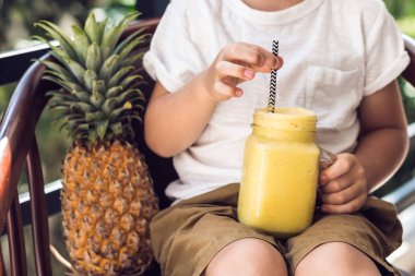 Çocuk bir ananas yüzlü terasta içiyor..