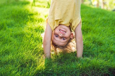 Baş aşağı açık havada eller üzerinde yürüme yaz parkta oynayan mutlu çocuk portresi