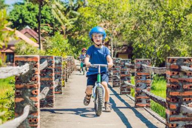 İki küçük çocuklar çocuklar eğleniyor denge bisiklet üzerinde bir ülke tropikal yolda.