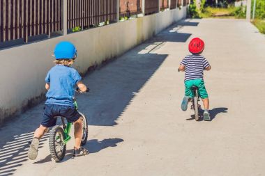 Two little boys children having fun on Balance Bike on a country tropical road. clipart