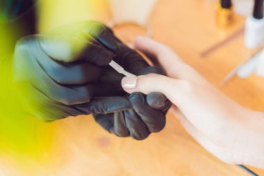 Closeup parmak tırnak bakım Güzellik Salonu manikür uzmanı tarafından. Manikürcü çivi oje ile boyar.