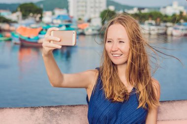 Güzel genç neşeli kadın arka planı Vietnamca tekneler ve deniz bir selfie alarak.
