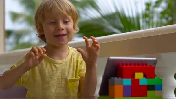 Niño en trópicos hablando con amigos y familiares en videollamada usando una tableta y auriculares inalámbricos — Vídeo de stock