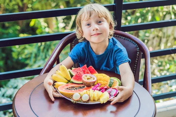Хлопчик їсть різні фрукти на терасі — стокове фото