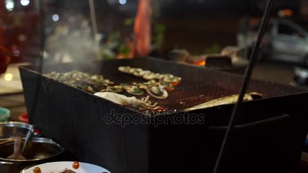 Lenta toma de un proceso de cocinar mariscos en una barbacoa en un mercado nocturno asiático — Vídeo de stock