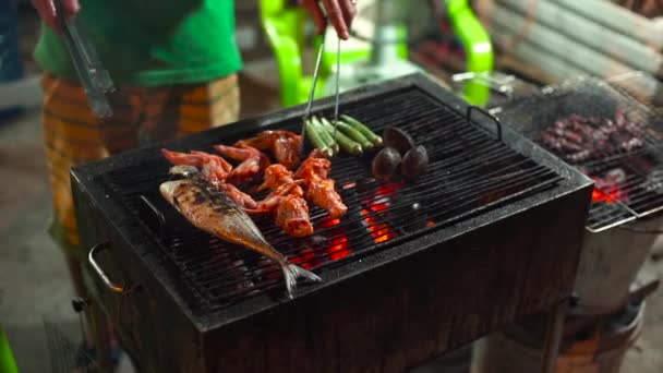 Langsom skud af en proces med madlavning fisk og skaldyr på en grill på et asiatisk natmarked – Stock-video