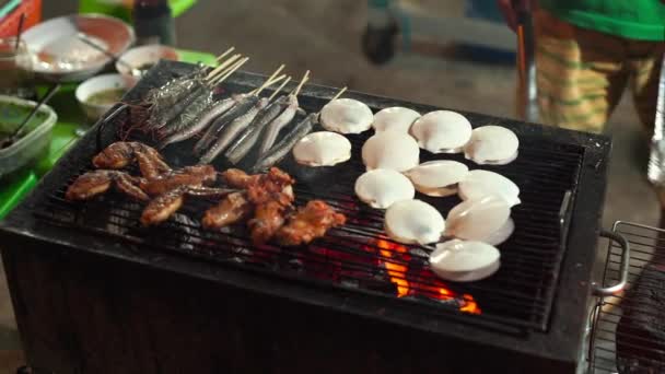 Langsom skud af en proces med madlavning fisk og skaldyr på en grill på et asiatisk natmarked – Stock-video