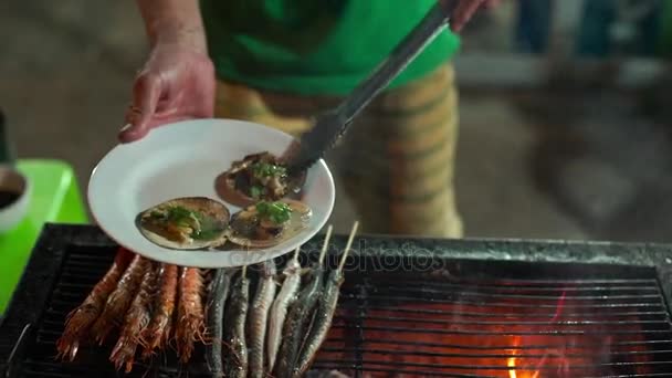 Lenta toma de un proceso de cocinar mariscos en una barbacoa en un mercado nocturno asiático — Vídeo de stock