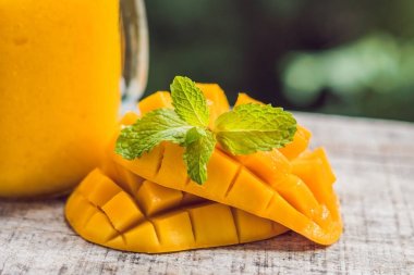 Mango smoothie cam Mason kavanoza ve mango yeşil bir backgro üzerinde