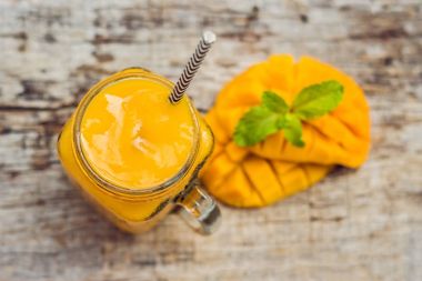 Mango smoothie cam Mason kavanoza ve mango yeşil bir backgro üzerinde