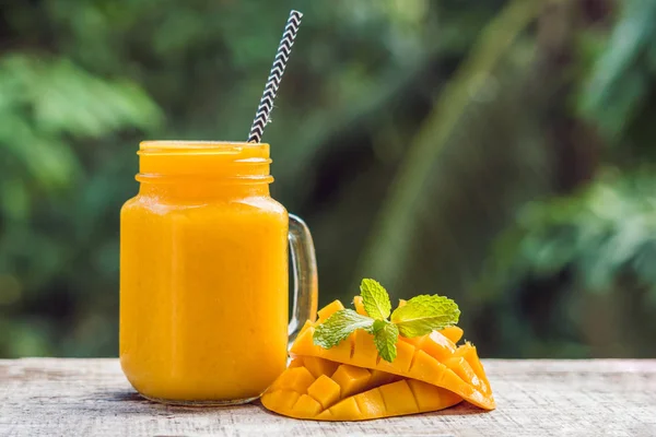 Mango smoothie i et glass Mason krukke og mango på en grønn backgro – stockfoto