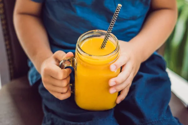 Chico bebiendo jugoso smoothie de mango en vidrio tarro de albañil con s — Foto de Stock