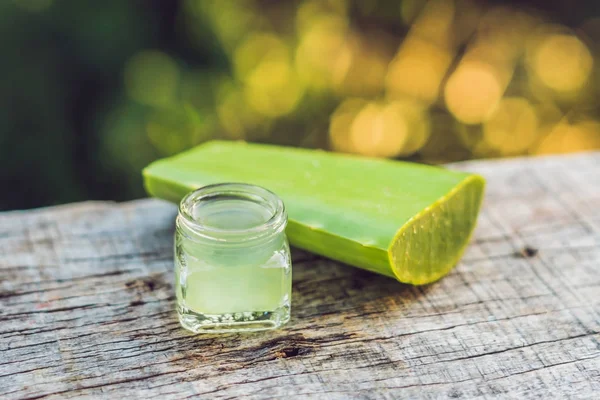 Slices of a aloe vera leaf and a bottle with transparent gel for medicinal purposes, skin treatment and cosmetics, close up — Stock Photo, Image