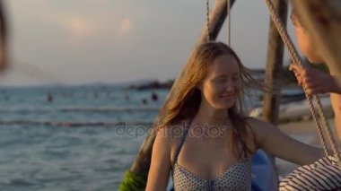 Genç kadın mutlu oğlu bir denizde ahşap bir salıncak üzerinde günbatımı teker teker salıncaklar