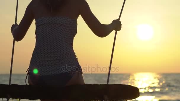 Щаслива жінка гойдається і розслабляється на мотузці з райським тропічним морем на задньому плані — стокове відео