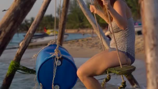 Gelukkige vrouw swingende en ontspannen op een schommel touw met een paradijs tropische zee op achtergrond — Stockvideo