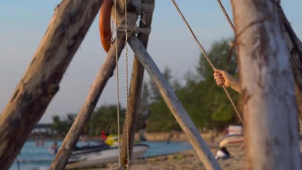 Femme heureuse balançant et se détendre sur une balançoire à corde avec une mer tropicale paradisiaque en arrière-plan — Video