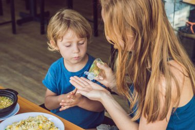 Anne ve oğlu yıkama el dezenfektanı kullanarak kafede jel.