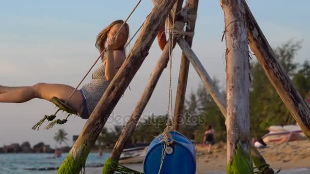Mujer feliz balanceándose en un columpio de cuerda con un paraíso tropical mar en el fondo — Vídeos de Stock