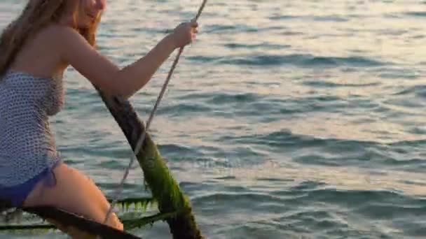 バック グラウンドでの楽園熱帯の海でロープ スイングを振る幸せな女 — ストック動画