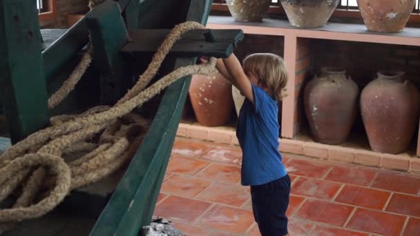 Mały chłopiec wizyty ekspozycja w Muzeum Narodowym na wyspie Phu Quoc island Wietnam, patrzy w starożytnej łodzi, wypełnione ceramiczne dzbanki — Wideo stockowe