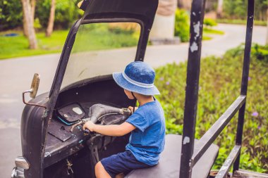 Parkta yaşlı bir üç tekerlekli bisiklet üstünde bir oğlan.