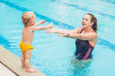 Genç anne küçük oğlu, öğretmek bir yüzme havuzunda yüzmeyi.