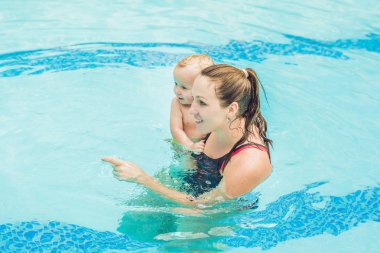 Genç anne küçük oğlu, öğretmek bir yüzme havuzunda yüzmeyi.