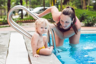 Genç anne küçük oğlu, öğretmek bir yüzme havuzunda yüzmeyi.