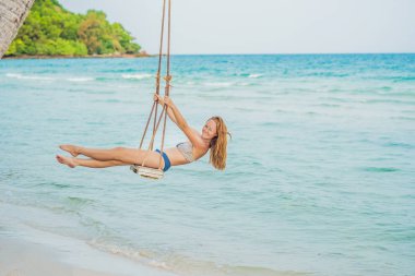 Tatil kavramı. Deniz manzarayı salıncakta oturan mutlu genç kadın.