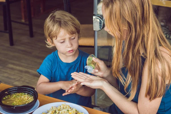 母と息子の洗浄ハンドサニタイザーを使用してゲルのカフェで — ストック写真