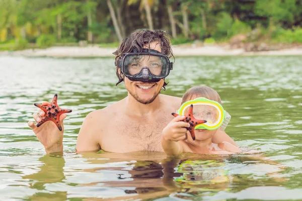 Padre e figlio mostrano una stella marina rossa sullo sfondo della s — Foto Stock