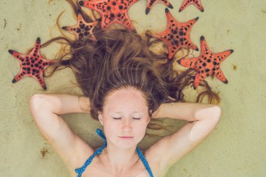 Kırmızı starfishes ile denizde genç kadın.