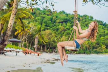 Tatil kavramı. Deniz manzarayı salıncakta oturan mutlu genç kadın.