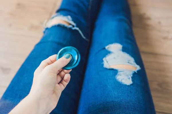 Menina adolescente em jeans holey segura nas mãos e brinca com spinner — Fotografia de Stock