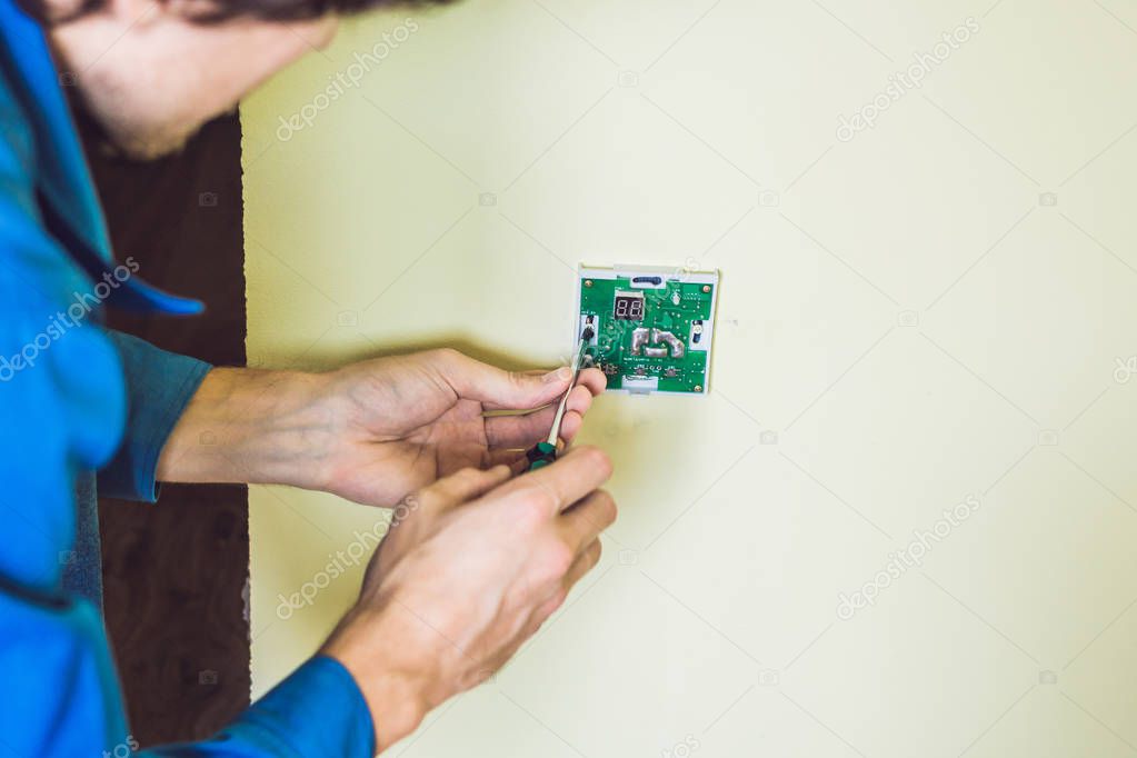 electrician installing an electrical thermostat in a new house.