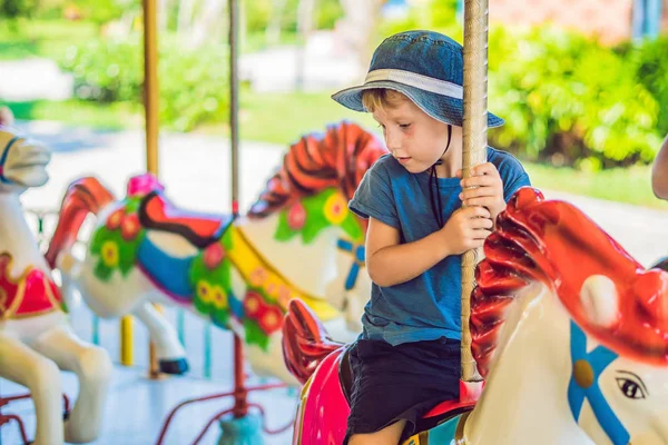 Mignon petit garçon profiter dans funfair et équitation sur coloré carrousel maison — Photo