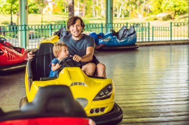 Baba oğul lunaparktaki çarpışan arabada geziyorlar.