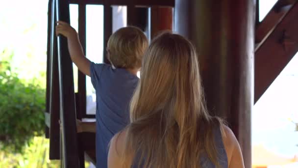 Mujer joven y su hijo subiendo las escaleras de madera hasta el segundo piso dentro de un templo budista Ho Quoc Pagoda en la isla de Phu Quoc, Vietnam — Vídeos de Stock