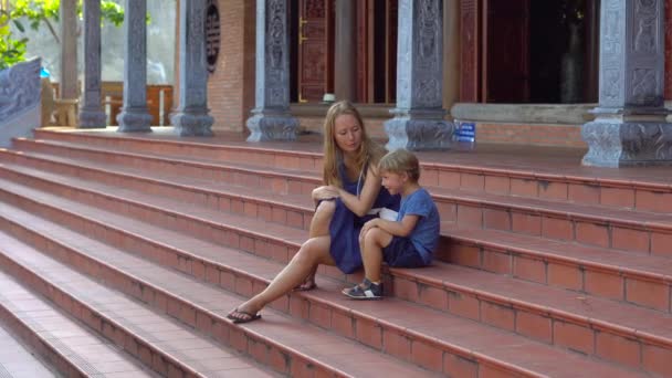 Steadycam shot of a young woman and her son visiting a budhist temple Ho Quoc Pagoda on Phu Quoc island, Vietnam — Stock Video