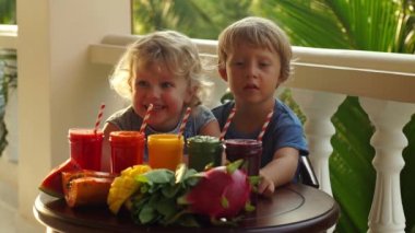 Çocuk renkli sağlıklı smoothies iç. Karpuz, papaya, mango, ıspanak ve dragon meyve. Smoothies, meyve suları, meyve suyu, içecekler, içecekler çeşitli taze meyve ile ahşap bir masaya.