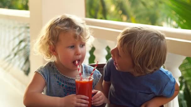 Slowmotion lövés. Aranyos kisfiú és a lány inni colorfull gyümölcsök rázza. Fiú mosolyogva a lány — Stock videók