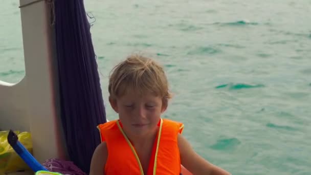 Маленький мальчик на лодке показывает свою маску и трубку перед своим первым плаванием в открытом море . — стоковое видео