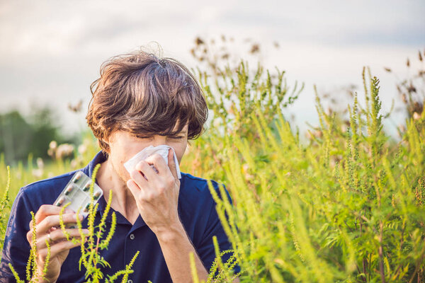 Young man sneezes because of an allergy to ragweed.