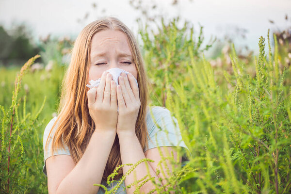 Young woman sneezes because of an allergy to ragweed.