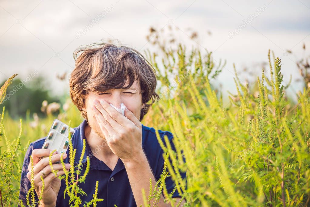 Young man sneezes because of an allergy to ragweed.