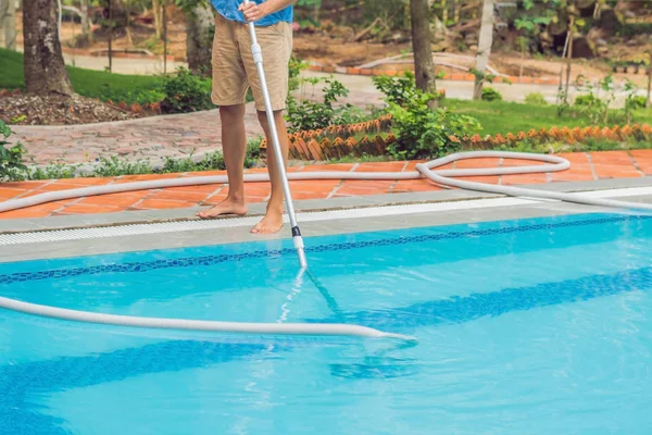 Cleaner of the swimming pool. Man with cleaning equipment for swimming pools, sunny.