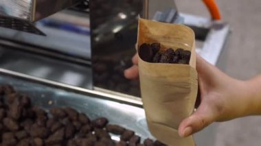 Asyalı kadın fryed kakao çekirdekleri sır bir kağıt torbaya koyar