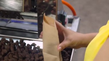 Asyalı kadın fryed kakao çekirdekleri sır bir kağıt torbaya koyar