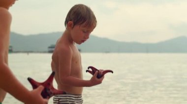 Çocuk starfishes bir denizde ile oynarken